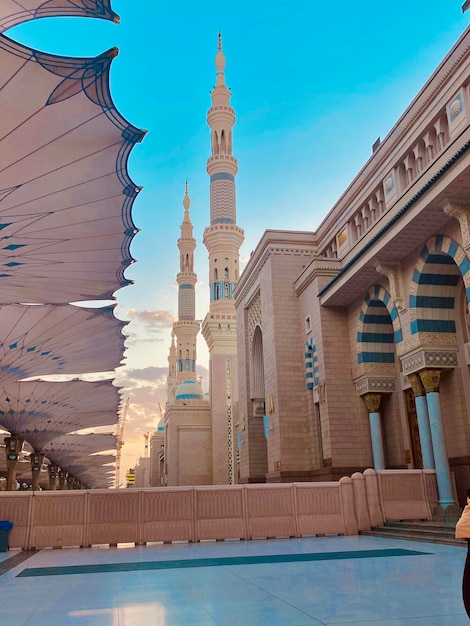 Une femme passe devant une mosquée avec un homme en chemise blanche.