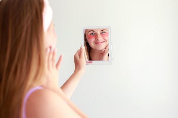 Une femme en patchs sous les yeux se regarde dans le miroir