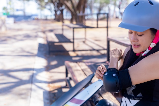 Femme patineuse avec casque mettant des coussinets de protection du coude