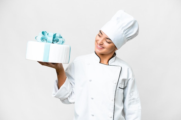 Photo une femme pâtissière avec un grand gâteau sur un fond blanc isolé avec une expression heureuse