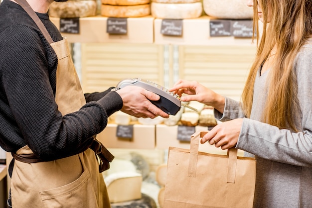 Femme payant avec carte dans le magasin d'alimentation achetant des fromages