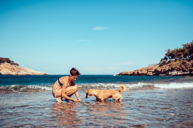 Femme payant avec un chien sur la plage