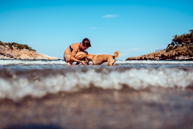 Femme payant avec un chien sur la plage