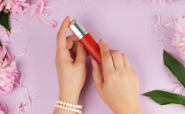 Femme à la peau claire et lisse garde le rouge à lèvres rouge liquide dans un tube