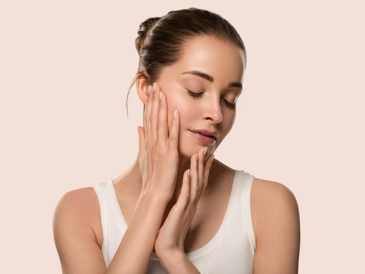 Photo femme de peau saine de beauté touchant son visage belle femelle. fond de couleur. rose