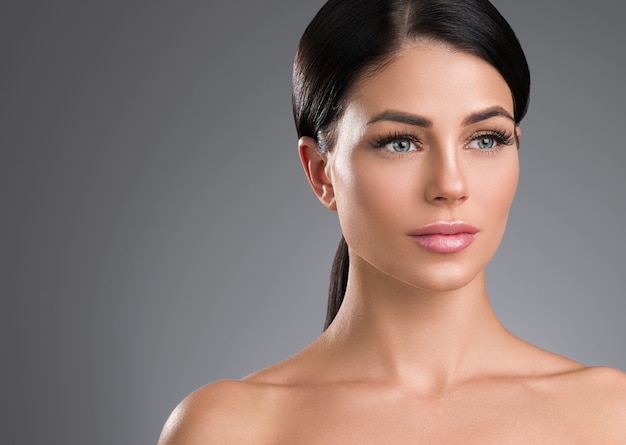 Femme peau saine extension de cils beauté maquillage naturel âge cosmétique concept fond gris. Prise de vue en studio.