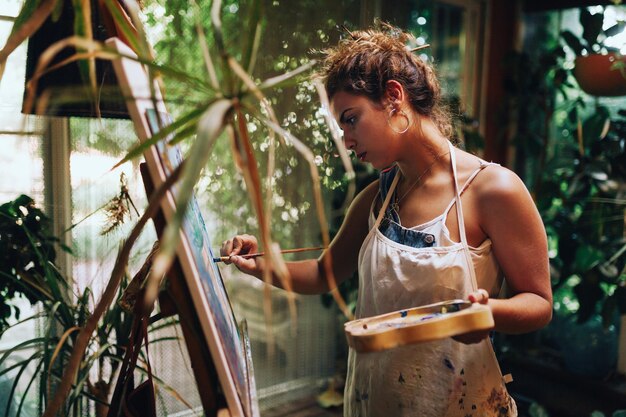 Photo femme peignant alors qu'elle est debout à la maison