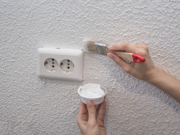 Femme peignant le mur. Restauration des murs blancs peints.