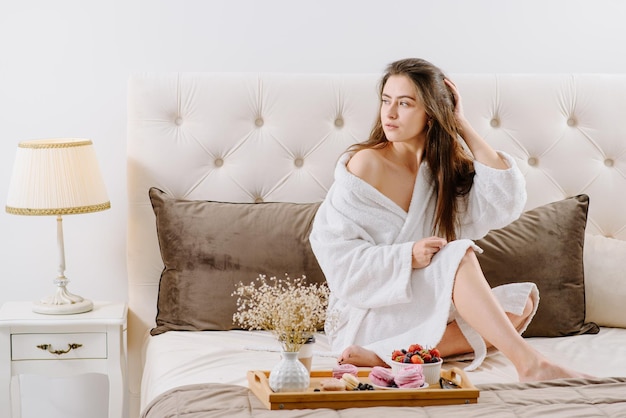 Une femme en peignoir se reposant sur le lit à la maison