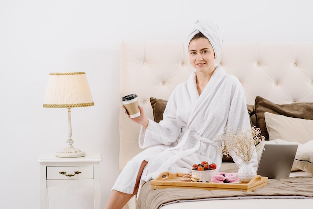 Une femme en peignoir se reposant sur le lit à la maison