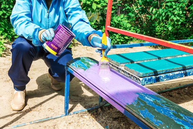 Photo une femme peint un banc avec de l'émail alkyd dans un terrain de jeu dans une maternelle