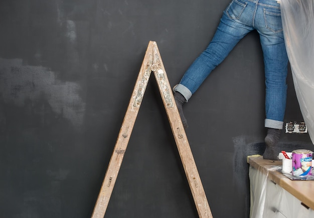 La femme peint le mur avec de la peinture noire Rénovation de la cuisine à domicile Réparation des appartements