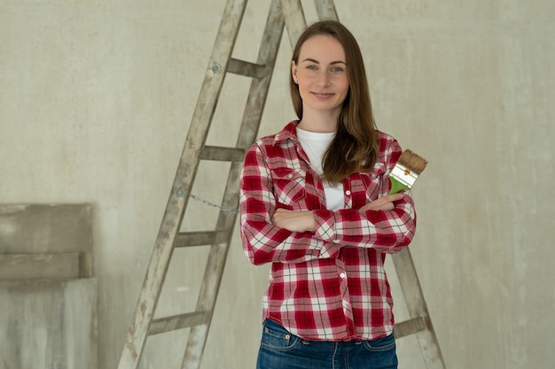 Femme peint les murs à la maison détient le concept de réparation de pinceau et de rénovation de maison