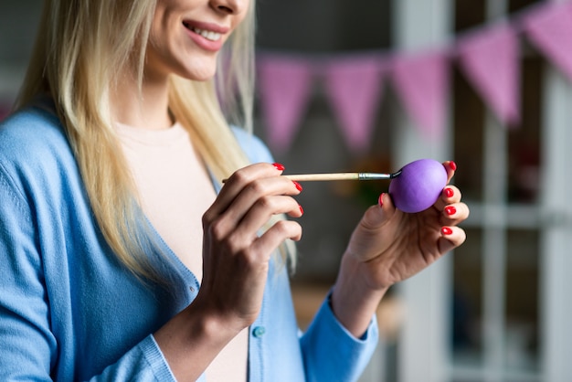 Une femme peint un oeuf de Pâques, vue rapprochée.