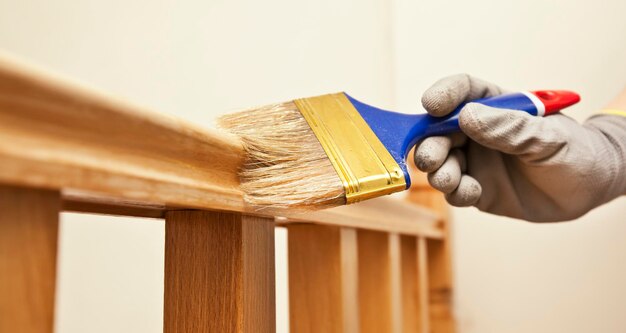 La femme peint une planche de bois vernis au pinceau