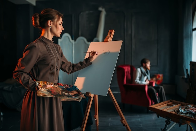 Femme peintre peint portrait d'homme en studio d'art