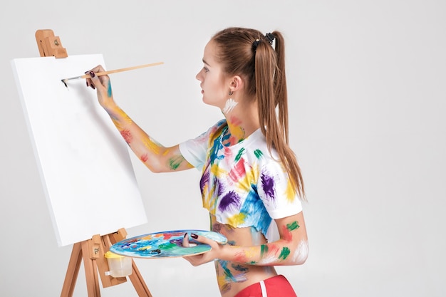 Femme peintre souillé de peinture colorée s'appuie sur toile