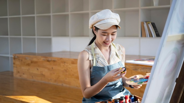 Femme peintre souriante peignant sur un chevalet dans son atelier