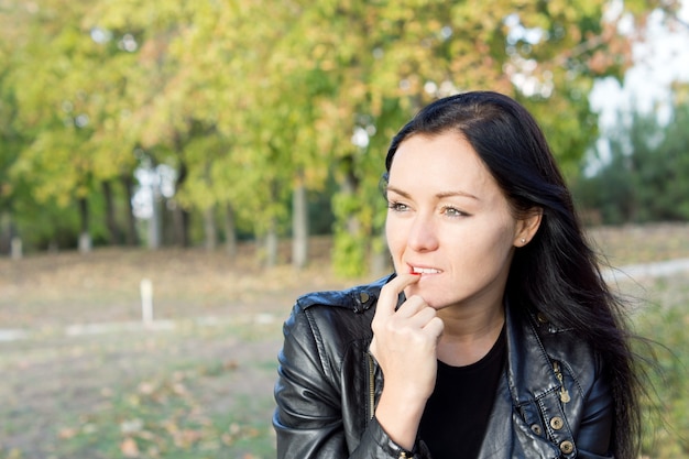 Femme pensive assise à l'extérieur dans la campagne en pensant et en regardant au loin