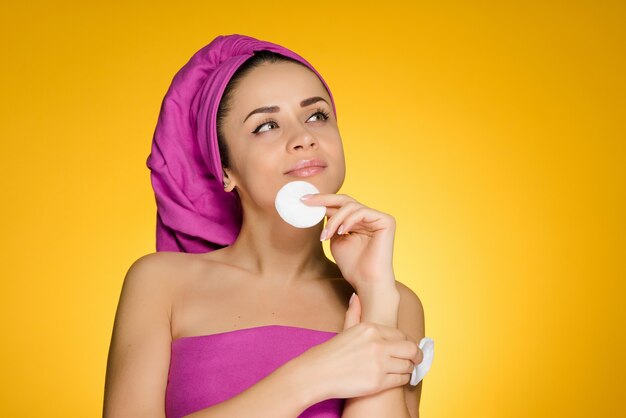 Une femme pensive avec une serviette sur la tête tient dans les mains des disques rembourrés