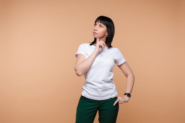 Une femme pensive en t-shirt blanc en levant.