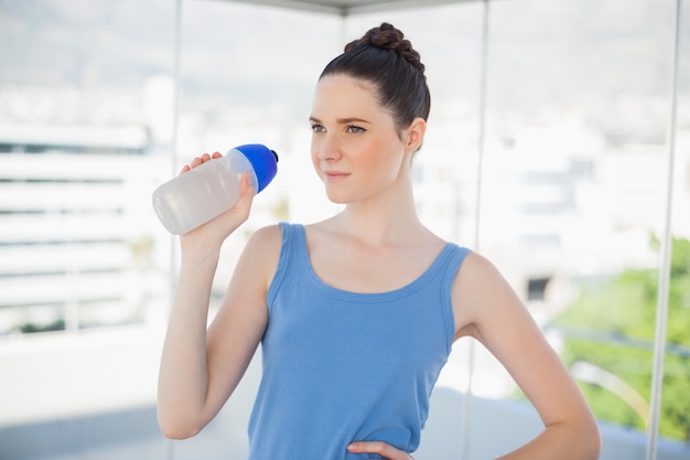 Femme pensive tenant une bouteille en plastique