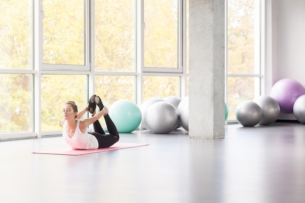 Femme avec petit sourire faisant du yoga, posture de l'arc, yoga. DhanurÄsana. Prise de vue en studio