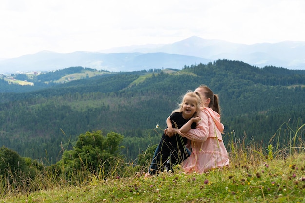 Femme et petite fille s'amusant sur la colline avec des montagnes derrière la vue extérieure d'été