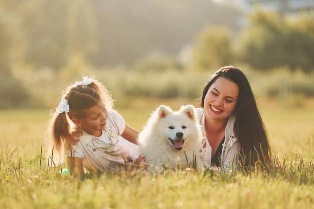 Une femme et une petite fille se promènent avec un chien sur le terrain pendant la journée ensoleillée