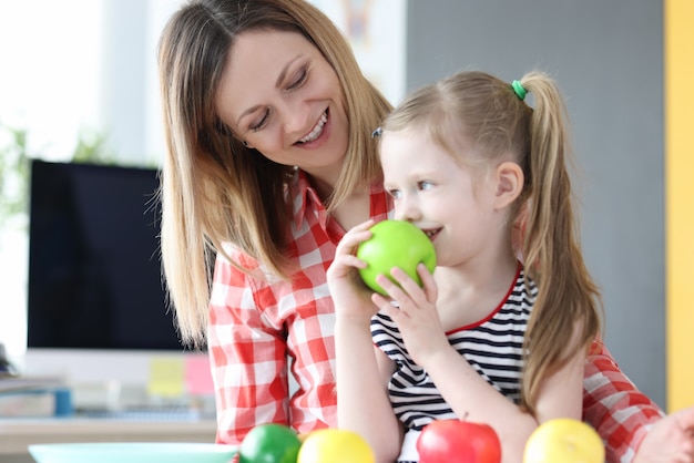 La femme a une petite fille sur ses genoux et a une pomme