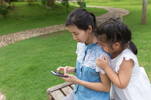 femme et petite fille avec téléphone portable sur le parc naturel