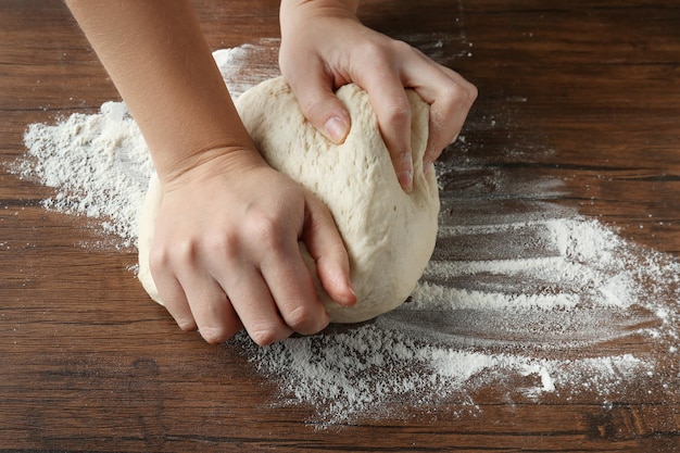 Femme pétrissant la pâte sur la table de cuisine en bois se bouchent