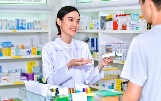 Femme pharmacien tenant une boîte de médicaments donnant des conseils au client en pharmacie