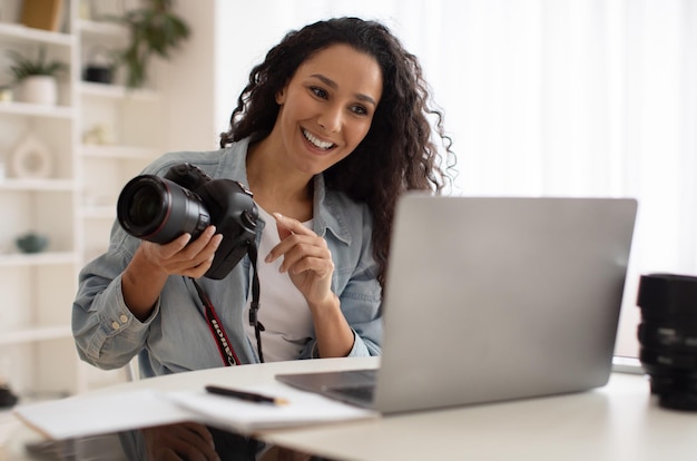 Femme photographe appel vidéo tenant une caméra enseignant la photographie en ligne à l'intérieur