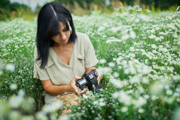 Femme photographe assise à l'extérieur sur un paysage de champ de fleurs tenant un appareil photo,