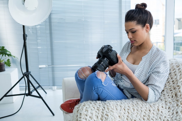 Femme photographe examinant des photos capturées dans son appareil photo numérique