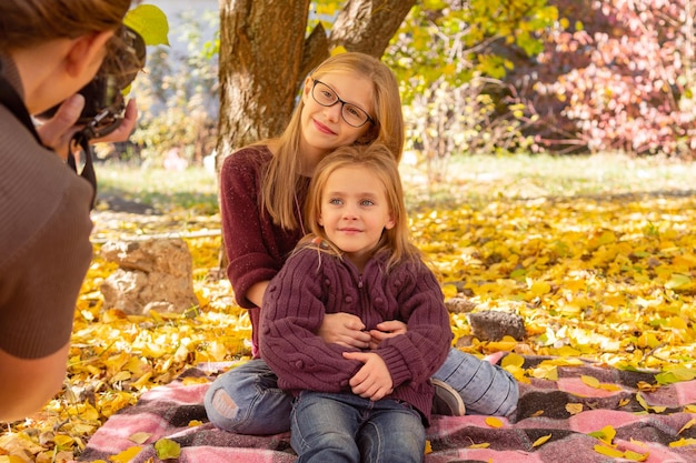 Femme photographe photographiant deux enfants parmi les feuilles d'automne