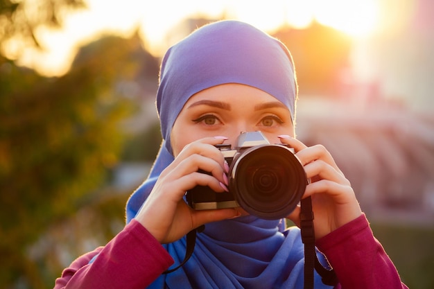 Photo femme photographe portant un hijab femme tenant un amateur de caméra ou un journaliste dans la forêt d'arbres d'automne du parc d'été
