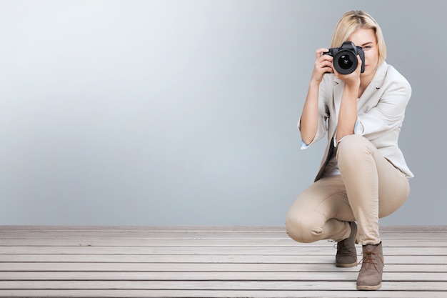 Une femme-photographe prend des photos assise sur un bureau dans la chambre