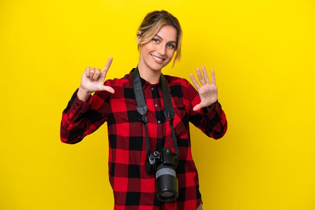 Femme photographe uruguayenne isolée sur fond jaune comptant sept avec les doigts