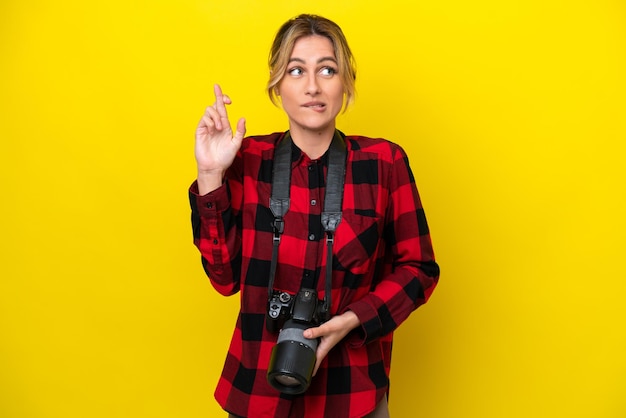 Photo femme photographe uruguayenne isolée sur fond jaune avec les doigts croisés et souhaitant le meilleur