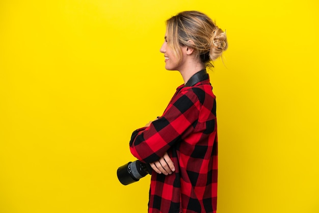 Femme photographe uruguayenne isolée sur fond jaune en position latérale