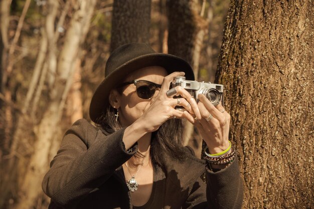 Une femme photographiant près du tronc d'un arbre