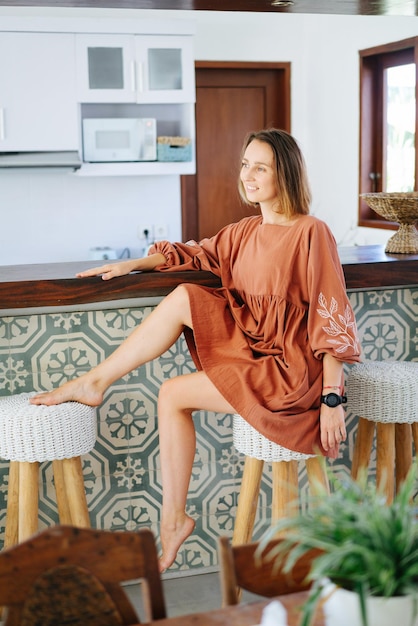 Une femme pieds nus dans une belle robe assise dans un bar d'été