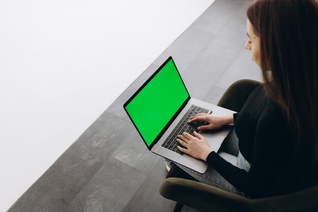 Femme pigiste à l'aide d'un ordinateur portable avec un écran vert sur le moniteur Concept de travail à distance