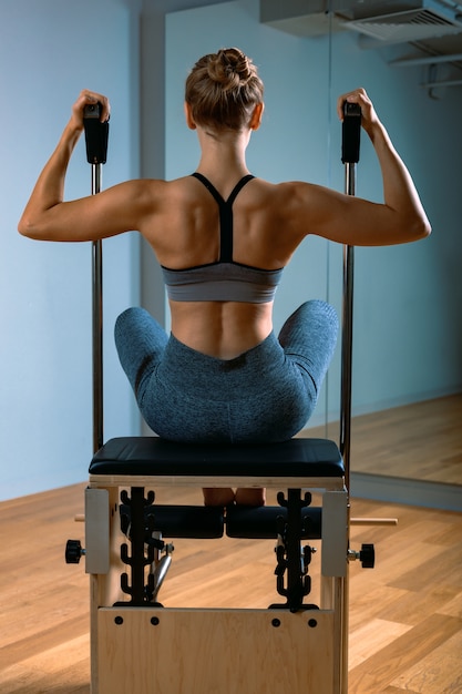 Femme Pilates dans un réformateur faisant des exercices d'étirement dans la salle de gym. Concept de remise en forme, équipement de fitness spécial, mode de vie sain, plastique. Espace copie, bannière sportive pour la publicité