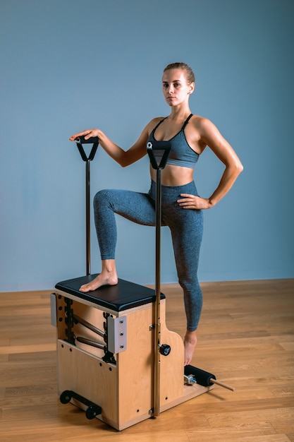 Femme Pilates dans un réformateur faisant des exercices d'étirement dans la salle de sport