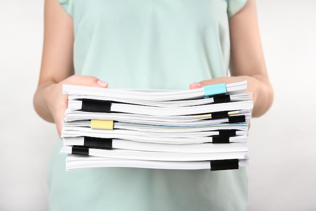 Femme avec pile de documents sur fond clair