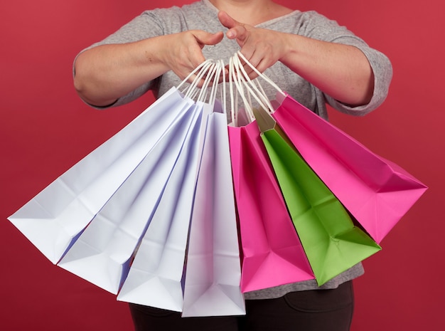 Femme avec pile de sacs en papier sur fond rouge