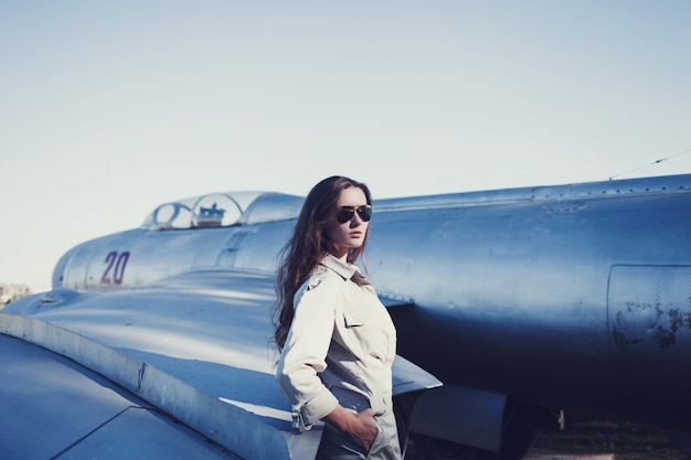 Femme pilote en lunettes de soleil près de l'avion